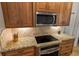 Kitchen featuring wooden cabinets, stainless steel microwave and oven, and granite countertops at 1254 Royal Pointe Ln, Ormond Beach, FL 32174