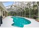 Spacious screened pool area with a spa, sun loungers, umbrella and tropical backdrop at 1254 Royal Pointe Ln, Ormond Beach, FL 32174