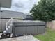Backyard featuring a gray hot tub with a cover next to an above-ground pool and surrounded by privacy fencing at 146 Via Madrid Dr, Ormond Beach, FL 32176