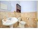 Bathroom with a pedestal sink, toilet, mirrored cabinet, and neutral-toned tile surround at 1650 Riverside Dr, Daytona Beach, FL 32117