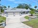 Charming single-story home featuring a gray roof, two-car garage, circular driveway, and landscaped front yard at 1650 Riverside Dr, Daytona Beach, FL 32117