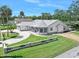 Beautiful single Gathering home with meticulously kept lawn, light gray color palette, and tropical trees at 1650 Riverside Dr, Daytona Beach, FL 32117