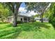 Expansive backyard with a view of the screened lanai and mature trees providing ample shade at 24 Katrinas Dr, Ormond Beach, FL 32174