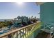 View of colorful houses and a swimming pool from a balcony with a white rocking chair at 3000 Ocean Shore Blvd # 18, Ormond Beach, FL 32176