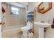 Bright bathroom features a shower-tub combo, pedestal sink, and convenient storage at 466 Leland Dr, Deltona, FL 32725