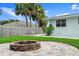 Backyard with paver patio, stone fire pit, lush grass and green space with privacy fence in background at 1026 Bel Aire Dr, Daytona Beach, FL 32118
