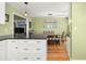 Bright kitchen with white cabinets, black countertops, stainless appliances, hardwood floors, and view to the dining room at 1026 Bel Aire Dr, Daytona Beach, FL 32118