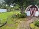 Backyard featuring lush landscaping, paver walkway, and a shed with red doors at 1218 Daytona Ave, Daytona Beach, FL 32117