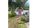 Backyard shed featuring a red and white paint job with adjacent landscaping at 1218 Daytona Ave, Daytona Beach, FL 32117