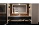 Modern bathroom featuring an illuminated mirror, dual sinks, and a tiled accent wall for a luxurious feel at 2360 Ocean Shore Blvd # 7, Ormond Beach, FL 32176