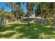 Lush backyard with a screened-in porch, mature trees, and a wood fence at 2531 Needle Palm Dr, Edgewater, FL 32141
