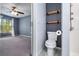 Bathroom with a toilet, overhead shelving, shower accessories, and doorway to a carpeted bedroom at 2531 Needle Palm Dr, Edgewater, FL 32141