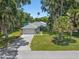 Charming single-story home with lush landscaping, mature trees, and a spacious driveway leading to an attached two-car garage at 2531 Needle Palm Dr, Edgewater, FL 32141