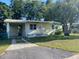 Charming single-story home featuring a carport, well-maintained lawn, and a mature tree providing ample shade at 264 Sherwood Ln, Daytona Beach, FL 32117