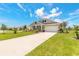Beautiful home boasts a long driveway, lush green lawn, and colorful landscaping under a sunny sky with scattered clouds at 2836 Monaghan Dr, Ormond Beach, FL 32174