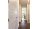 Hallway with wood-look tile floors, white doors, and view into the naturally lit bath and laundry areas at 2836 Monaghan Dr, Ormond Beach, FL 32174