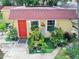 Cozy single-story home with a red roof and door surrounded by lush greenery at 918 N Wild Olive Ave, Daytona Beach, FL 32118