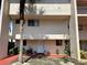 Exterior shot of a well-maintained condo building with a red walkway, palm trees, and a white front door at 1162 Carmel Cir # 100, Casselberry, FL 32707