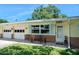 Charming single-story home with yellow siding, brick accents, well-manicured lawn, mature trees, and an attached two-car garage at 1505 Valencia Ave, Daytona Beach, FL 32117