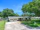 Charming single-story home with yellow siding, brick accents, well-manicured lawn, mature trees, and an attached two-car garage at 1505 Valencia Ave, Daytona Beach, FL 32117