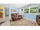 Cozy living room features blue walls, a large window, and a comfortable leather loveseat at 1505 Valencia Ave, Daytona Beach, FL 32117