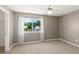 Well-lit bedroom with a ceiling fan, neutral walls, and a large window offering pleasant views of the surrounding landscape at 3522 Forest Branch Dr # D, Port Orange, FL 32129