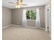 Bright bedroom with neutral walls, a ceiling fan, carpet, and a large window offering outdoor views at 3522 Forest Branch Dr # D, Port Orange, FL 32129
