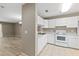 A well-lit kitchen featuring white appliances and cabinets adjacent to a dining area with modern flooring at 3522 Forest Branch Dr # D, Port Orange, FL 32129