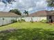 Large backyard featuring a lush green lawn, a white fence, and a swing set for outdoor enjoyment at 465 Dahoon Holly Dr, Daytona Beach, FL 32117