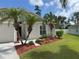 Inviting single-story home with a manicured lawn, featuring palm trees and colorful flowerbeds at 465 Dahoon Holly Dr, Daytona Beach, FL 32117