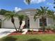 Charming single-story home with a well-manicured lawn and tropical landscaping, including palm trees at 465 Dahoon Holly Dr, Daytona Beach, FL 32117
