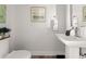 Half bathroom features a pedestal sink, modern toilet, and decorative artwork at 506 Dorset Cir, South Daytona, FL 32119