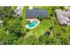 Aerial shot of a private backyard featuring a pool, trampoline and surrounding mature trees at 950 Pineapple Rd, South Daytona, FL 32119