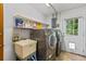 Bright laundry room with sink, shelving, modern washer and dryer, and an exterior door at 950 Pineapple Rd, South Daytona, FL 32119