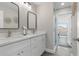Bright bathroom features a double vanity with white cabinets, modern faucets, and a glass-enclosed shower at 105 Bonita Pl, Ormond Beach, FL 32174