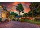 Backyard at dusk with patio, mature trees, tropical landscaping and string lights at 1221 Gamble Pl, Daytona Beach, FL 32118