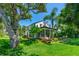 Expansive two-story home showcasing a screened-in porch and upper balcony, surrounded by lush landscaping and mature trees at 1221 Gamble Pl, Daytona Beach, FL 32118