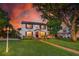 Charming two-story home with manicured lawn and brick walkway to the front door, highlighted by evening's warm lighting at 1221 Gamble Pl, Daytona Beach, FL 32118