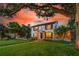 Elegant two-story home with manicured lawn, mature trees, and a brick walkway leading to the inviting entrance under a vibrant sunset at 1221 Gamble Pl, Daytona Beach, FL 32118