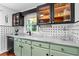 Stylish kitchen featuring pale green cabinets, black hardware, marble countertops, and glass-front upper cabinets at 1221 Gamble Pl, Daytona Beach, FL 32118
