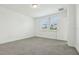 Light-filled bedroom with neutral carpeting, two large windows, and a white interior door at 288 Links Terrace Blvd, Daytona Beach, FL 32124