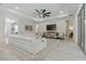 Bright living room with a white sectional sofa, tray ceiling with fan, stylish TV console, and light wood-look flooring at 3029 Adrian Dr, Ormond Beach, FL 32174