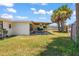 A cozy backyard seating area with patio, grass lawn, and tropical landscaping, shaded by a wooden pergola at 1 Beechwood Dr, Ormond Beach, FL 32176