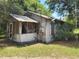 Weathered single story home with peeling paint, screened porch and overgrown landscaping at 110 Montclair Rd, Leesburg, FL 34748