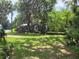 Overgrown front yard with view of run-down house almost hidden behind trees and shrubbery at 110 Montclair Rd, Leesburg, FL 34748
