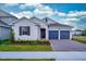 Two-car garage, light beige house with dark shutters and landscaping at 13200 Peaceful Melody Dr, Winter Garden, FL 34787