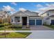 Two-story house with gray siding, blue garage doors, and landscaping at 13230 Peaceful Melody Dr, Winter Garden, FL 34787