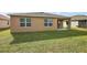 View of the home's backyard with green grass, two windows, and a covered patio area for relaxing at 2720 Dumont Ln, Tavares, FL 32778