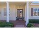 Front entrance with columns, brick walkway, and potted plants at 2441 Prairie Dunes, Clermont, FL 34711