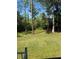 Backyard features a large grassy area with mature trees and lush landscaping at 32676 Oak Park Dr, Leesburg, FL 34748
